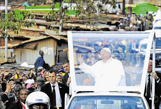 TOUGH MESSAGE: Pope Francis arrives in a Nairobi slum, shablasted waves as he arrives at the Nairobi shanty town where he blasted of Kangemi on November 27, 2015 in the Kenyan capital, Nairobi. Pope Francis lashed out at wealthy minorities who hoard resources at the expense of the poor and ‘cling to power and wealth ... , who selfishly squander while a growing majority is forced to flee to abandoned, filthy and run-down peripheries’