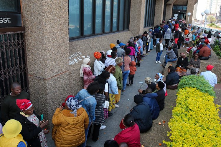 Grant recipients wait in a long queue for their payouts. File photo.