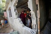 A Palestinian woman looks out of her house damaged in a nearby Israel bombing at Hamas sites over fire balloons into Israel, in Beit Hanoun in the northern Gaza Strip August 29, 2021. 