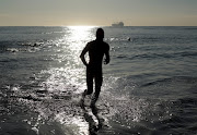 A swimmer in silhouette as he finishes during the World Ocean Day Swim at the Point Waterfront in Durban.