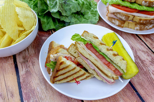 Two pieces of a Picnic Club on a plate with a pickle.