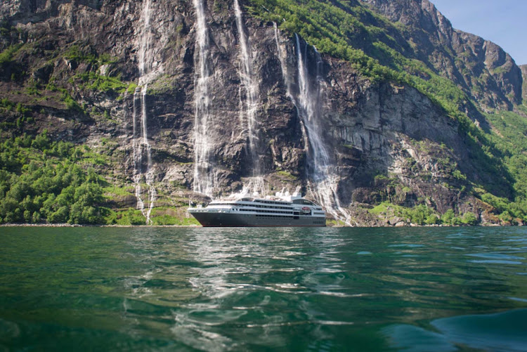 The Ponant ship L'Austral passes a waterfall in the Geiranger Fjord of Norway.