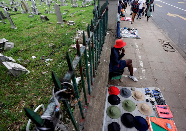 A group of street traders line up along the fence of a graveyard on West Street, Durban, to sell their wares.