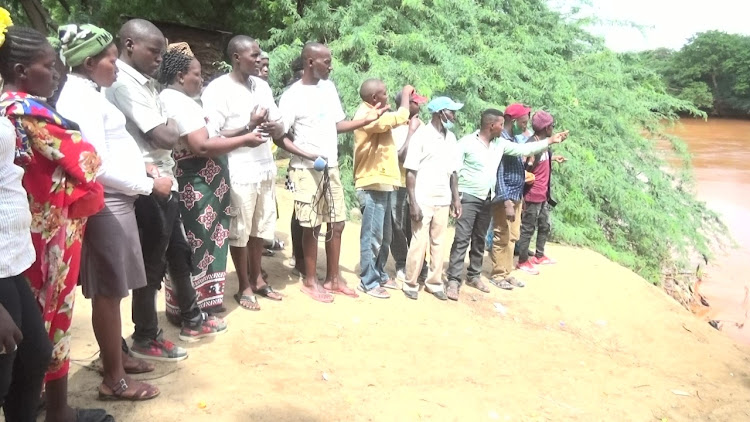 Family of the late Kennedy Muthuvi Mwende and curious onlookers congregate at the banks of river Tana as the search for the body continue and Garissa MCA Teresia Titus addressing the press.The family is appealing to the government to assist with specialized divers from the Navy and other agencies to help trace and retrieve the body from the crocodile infested river.