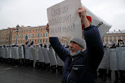 A demonstrator holds a placard reading 