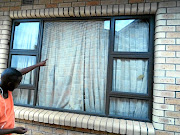 Siyamthanda Sogoni points to the house windows with no burglar proofing after his mother had paid R18,000. 