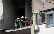 Rescue workers evacuate a person from a residential building damaged by a Russian missile strike, as Russia's attack on Ukraine continues, in Kyiv, Ukraine June 26, 2022.