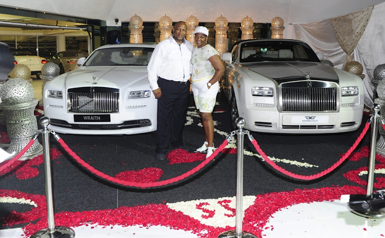 S’bu and Shauwn Mpisane pose with their two Rolls-Royces. Each bought the other one of these expensive cars and showed them off at their end-of-year party in 2013.