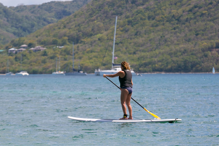 A Windstar passenger tries stand-up paddleboarding during the Windstar Island Experience beach party in St. Lucia.