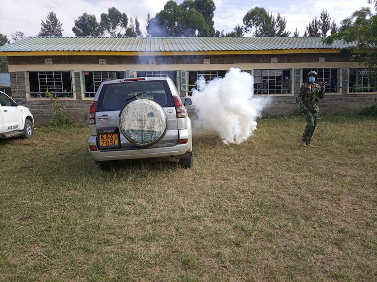 A tear gas canister lands next to a police officer at Milimani polling station. Police used tear gas to disperse rival groups.