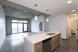 View from kitchen island looking into living room with concrete floors and large windows