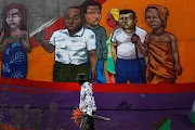 A man, who gave his name as Sipho, walks past a brightly-coloured mural, on Louis Botha Avenue in Johannesburg,on April 27 2020, while holding a bunch of flowers,during the extended Covid-19 lockdown. 