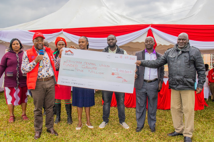 Kirinyaga ccntral MP Munene Wambugu presents a dummy cheque to representatives of the 83 groups.