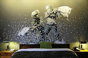 The rooms in the Walled Off hotel in Bethlehem invite guests to sleep inside works of art. This one features a Banksy wall painting of an Israeli border policeman and Palestinian in a pillow fight.