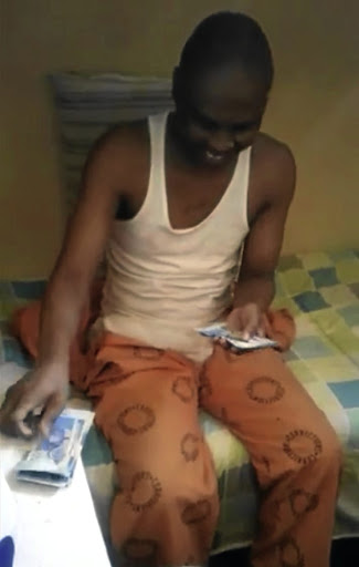 A screen grab from a video where a prisoner at Kgosi Mampuru II prison is seen gleefully counting cash in his cell.