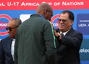 Confederation of African Football (Caf) president Ahmed Ahmed (L) looks while SA Football Association (Safa) President Danny Jordaan hands over the SA Under-17 men's national team head coach Molefi Petrus Ntseki (M) during the Cosafa Under 17 Youth Championships final match between South Africa and Angola at the Francois Xavier Stadium in Port Louis, Mauritius on July 29 2018.