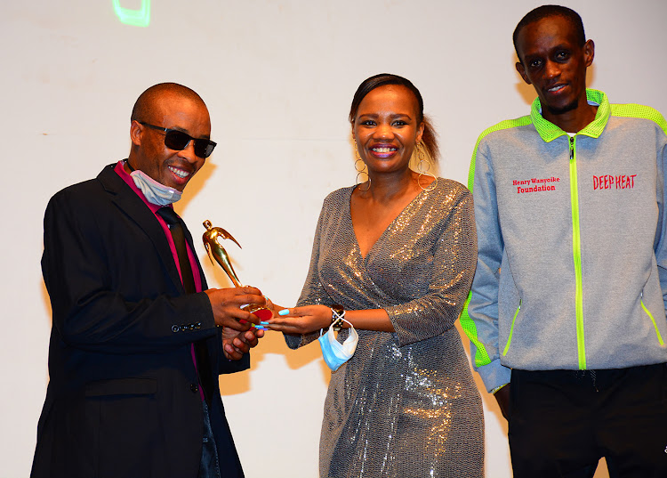 Safaricom's Peris Nduta presents the Most Resilient Sportsman with Disability Award to Henry Wanyoike as his guide, Paul Kihumba looks on