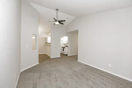 Living room with brown carpet, light gray walls, and ceiling fan