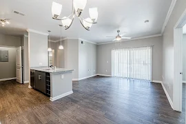 Spacious apartment interior featuring open layout, fixtures, and a large sliding glass door with natural light.