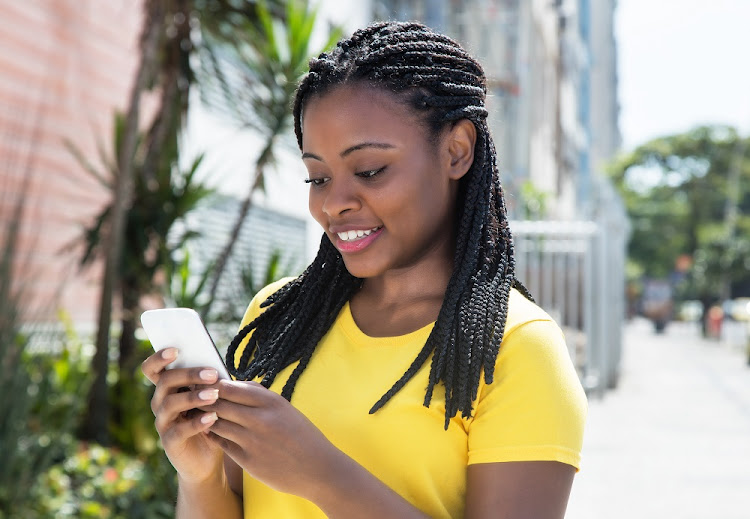 A generic image of woman in a yellow shirt using a smartphone.