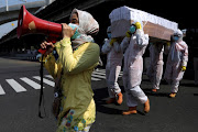 Government workers wearing protective suits carry a mock-up of a coffin of a Covid-19 victim to warn people about the dangers of the disease as the outbreak continues in Jakarta, Indonesia, August 28, 2020. 