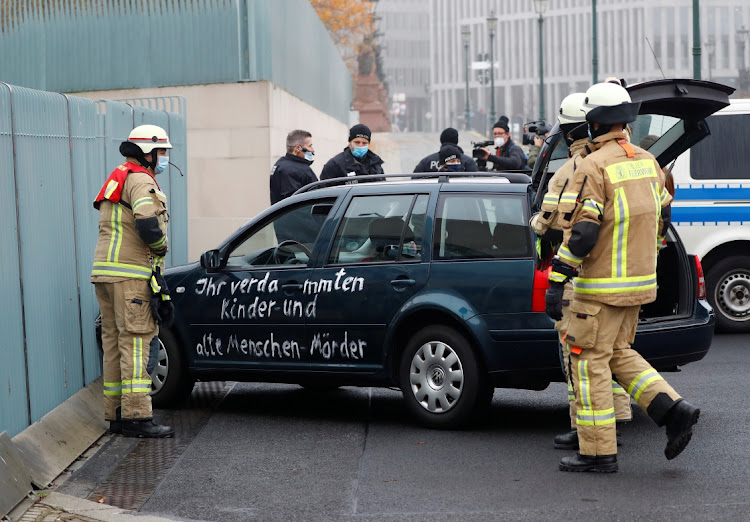 Firefighters remove the car which crashed into the gate of the main entrance of the chancellery in Berlin, the office of German Chancellor Angela Merkel in Berlin, Germany, November 25, 2020. Letters written on the car read: "You damn killers of children and old people".