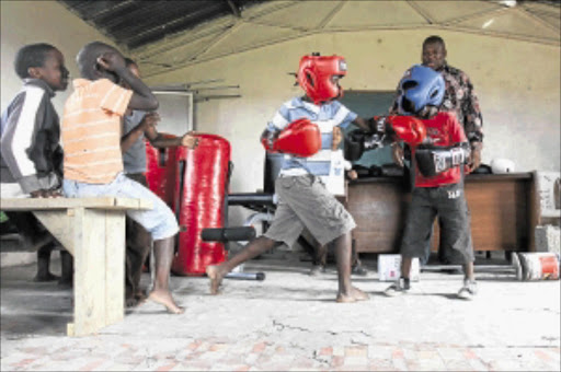 FUTURE STARS: BSA director of operations Loyiso Mtya looks on as youngsters from Mount Coke slug it out with the new kit sponsored by Mtya. Photo: MARK ANDREWS