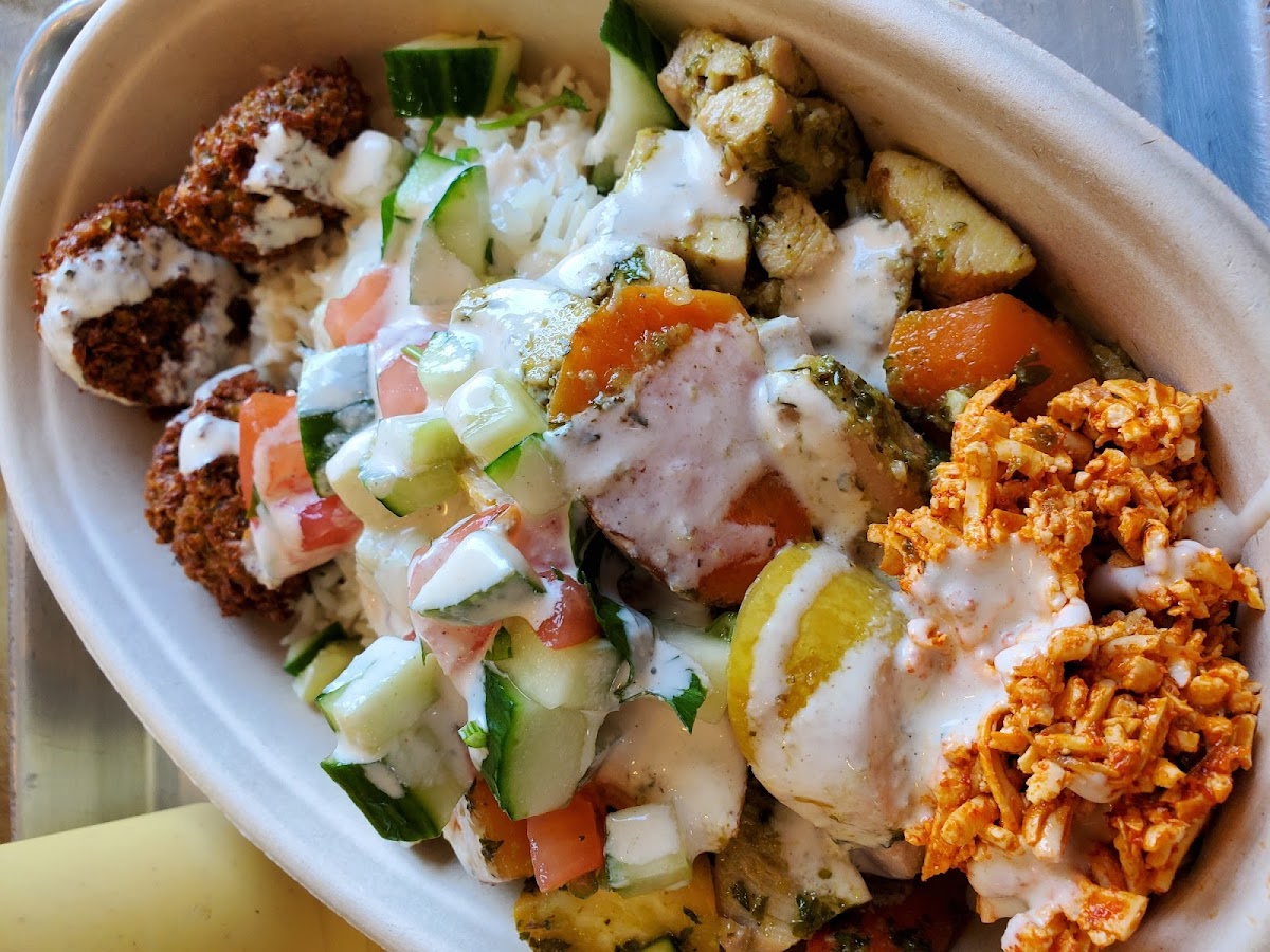 Rice bowl with lemon chicken and falafel and a whole bunch of toppings.