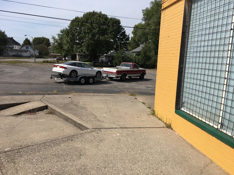 Car on a trailer behind a red truck