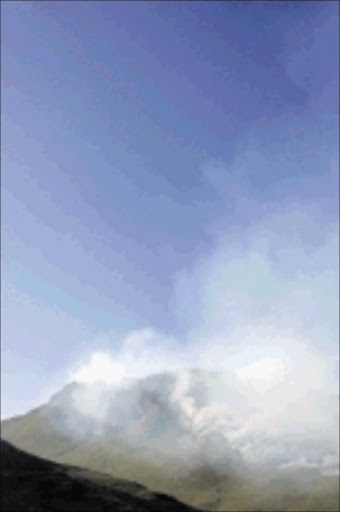 BILLOWING: Smoke seen on top of a mountain during a fire on the outskirts of Grabouw town on Wednesday. 25/02/09. Pic. Schalk van Zuydam. © AP.