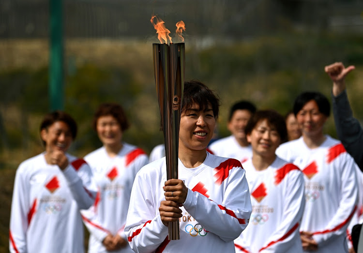 Japanese torchbearer Azusa Iwashimizu, a member of the Japan women's national football team, arrives at a torch "kiss point" to pass on the flame during the torch relay grand start at the J-Village National Training Centre in Naraha town, Fukushima Prefecture, Japan on March 25, 2021