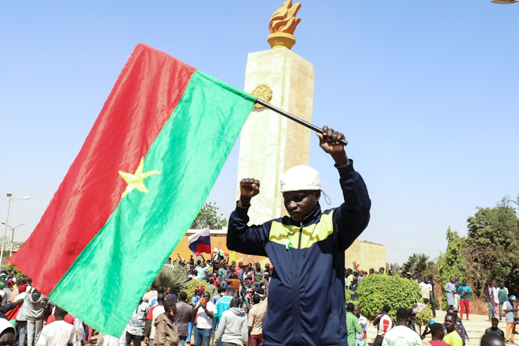 A man holds a national flag as people gather in support of a coup that ousted president Roch Kabore, in Ouagadougou, Burkina Faso, January 25 2022. Picture: VINCENT BADO/REUTERS