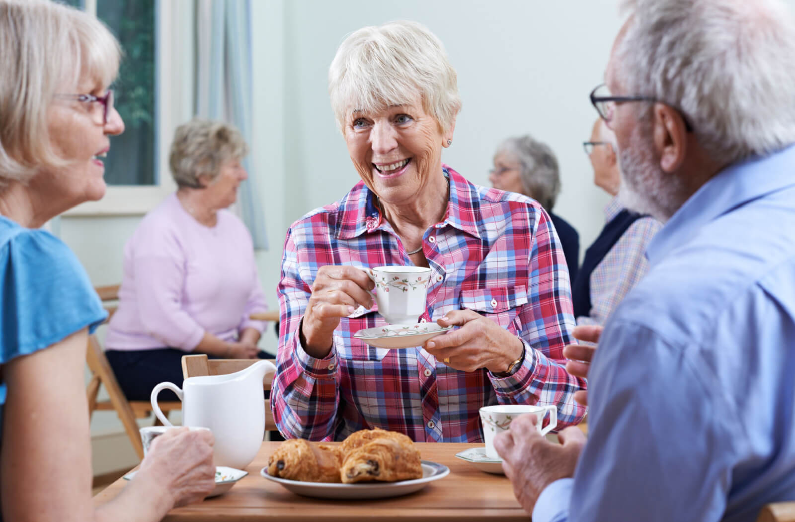 a group of seniors socialize over snacks and tea to keep memory sharp