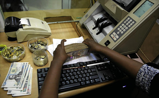 CAPITAL CRUNCH: A teller counts Kenyan currency inside the cashier's booth of a foreign exchange bureau in the capital, Nairobi.