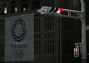 A banner for the upcoming Tokyo 2020 Olympics is seen behind traffic lights in Tokyo, Japan, on March 23 2020. 