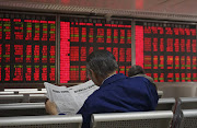 An investor reads the finance section of a newspaper at a brokerage in Beijing. China’s stock market shutdown in January hit many stocks on the JSE.