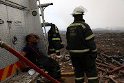 Firefighters rest as they wait for more water at the Msunduzi landfill in Pietermaritzburg.