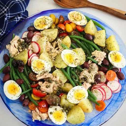 A delectable salad of  fresh vegetables, red potatoes, hard boiled eggs, Nicoise olives and tuna drizzled with an easy six ingredient mustard vinaigrette.
