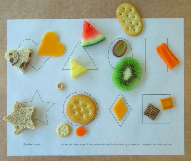 snacks like pieces of bread, cheese, crackers, watermelon slice, kiwi slice, pineapple slice in various shapes such as circle, square, triangle, heart, rectangle on a piece of white paper with shapes drawn on it