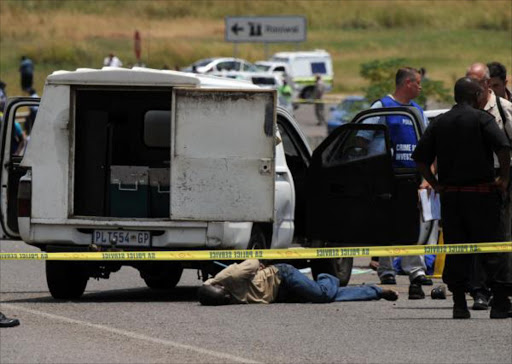 A suspect, under heavy police guard, lies on the road after a foiled cash-in-transit heist. File photo.