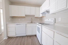 Kitchen with white cabinets, stone inspired countertops, and white appliances 