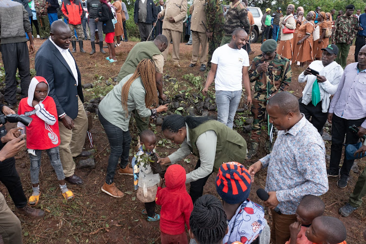 Environment CS Soipan Tuya interacts with a young boy during the national tree planting day at Kiambicho Forest Karua Hill A, Murang'a County, on May 10, 2024.