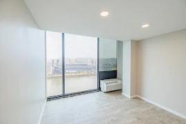 Bedroom with floor to celing windows and an air unjt. Rom has wood flooring, grey walls and canned lights.