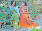 Yonela Mja, left, pairs a vintage isishweshwe dress with an oversized denim jacket, while her sister, Aviwe, complements her dress, in Da Gama Textiles’s pumpkin shade, with a sleeveless knitted top and leather jacket.