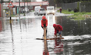 Kids from Hanover Park on the Caper Flats plays on a pallette on a waterlogged road outside their home. Heavy rains and strong winds cause flooding, waterlogged roads on the Cape Falts and informal settlements in the Western Cape