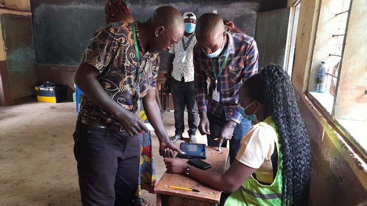 Jubilee's Donald Fundi verifying his details before casting his vote at Timbila Primary Polling Station