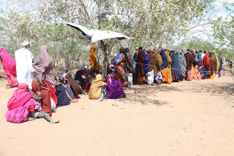 Voters, mostly women, many in heat absorbing dark colours, queue under the scorching sun in the bush at Garufu mobile polling station in Galole, Tana River county, on August 9