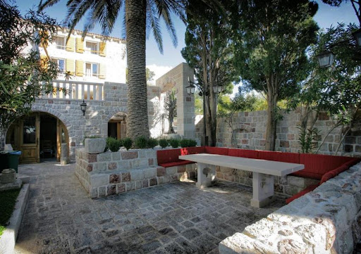 Paved terrace with red benches and stone table in this luxury property for sale in Budva ($1,154,108 - 260 m²)