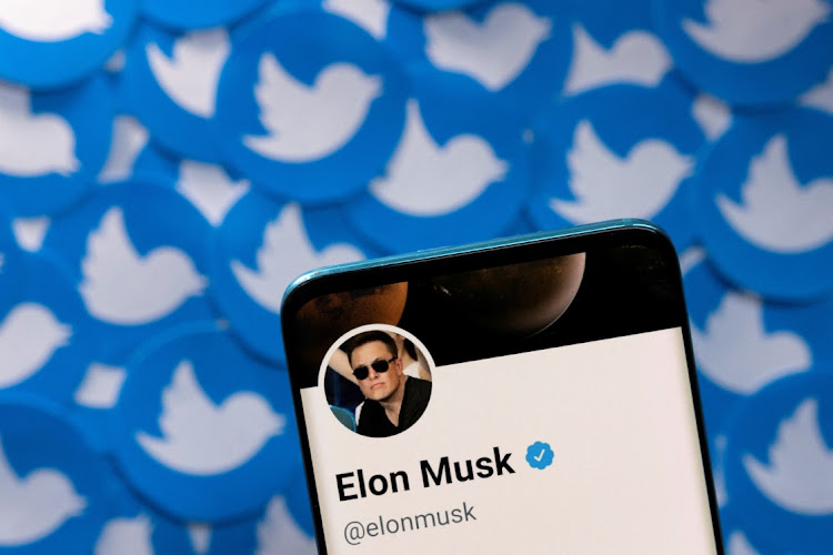 Elon Musk's Twitter profile is seen on a smartphone placed on printed Twitter logos in this picture illustration.