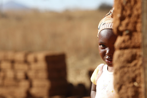 A young girl peeks at visitors at her home in Magangangosi. The village is outside of Bergville in KwaZulu-Natal. Pic: Shelley Christians.